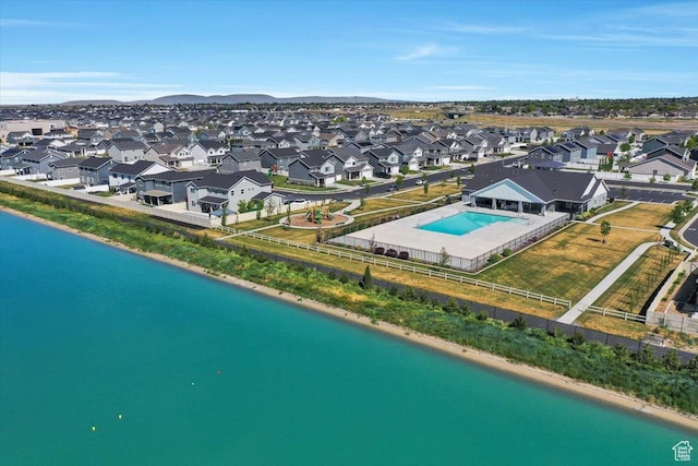 aerial perspective of suburban area featuring a pool and a nearby body of water