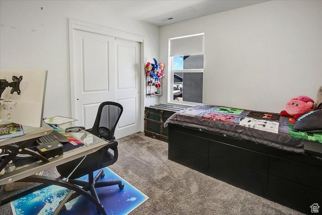 carpeted bedroom featuring an office area and a closet