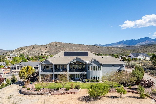 rear view of house featuring a balcony, solar panels, and a mountain view