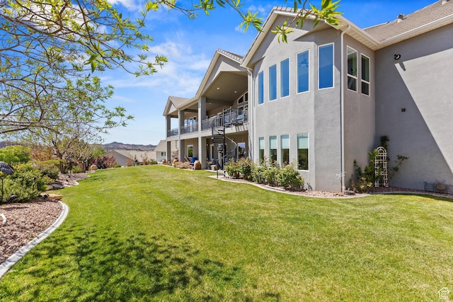 rear view of property featuring stucco siding, stairway, and a yard