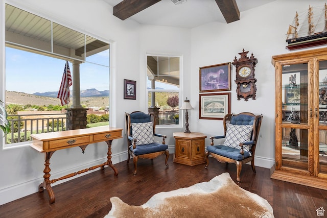 sitting room featuring a mountain view, beamed ceiling, hardwood / wood-style flooring, baseboards, and decorative columns