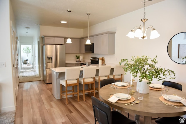 dining room with light wood-style flooring and a chandelier