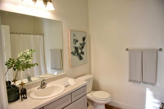 bathroom featuring toilet, vanity, and curtained shower