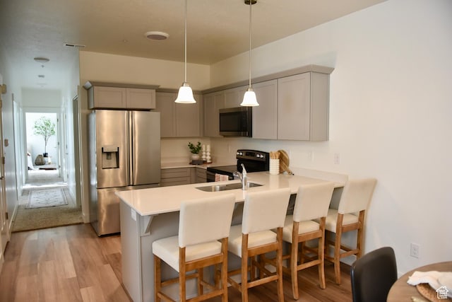 kitchen featuring stainless steel appliances, gray cabinetry, a peninsula, and a breakfast bar