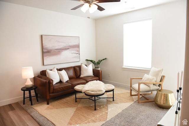 living area featuring a ceiling fan, baseboards, and wood finished floors