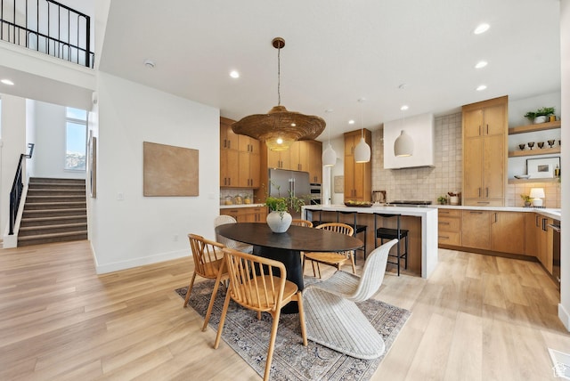 dining room with light wood-style floors, recessed lighting, stairs, and baseboards
