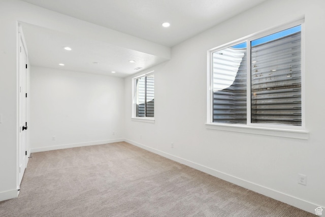 spare room with baseboards, recessed lighting, and light colored carpet