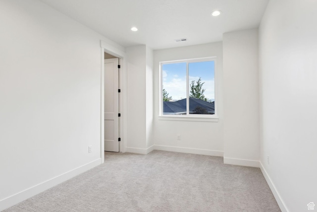 spare room featuring recessed lighting, light carpet, and baseboards