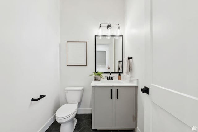 half bathroom featuring baseboards, toilet, vanity, and tile patterned floors