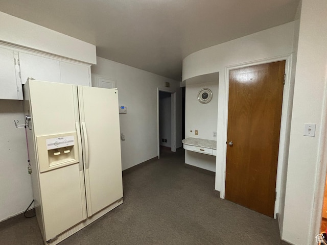 kitchen featuring white fridge with ice dispenser, white cabinets, dark carpet, and light countertops