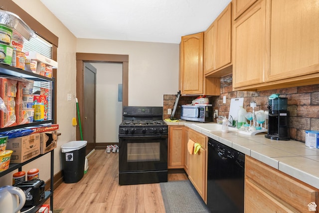 kitchen featuring black appliances, tile countertops, tasteful backsplash, light wood-style floors, and light brown cabinets