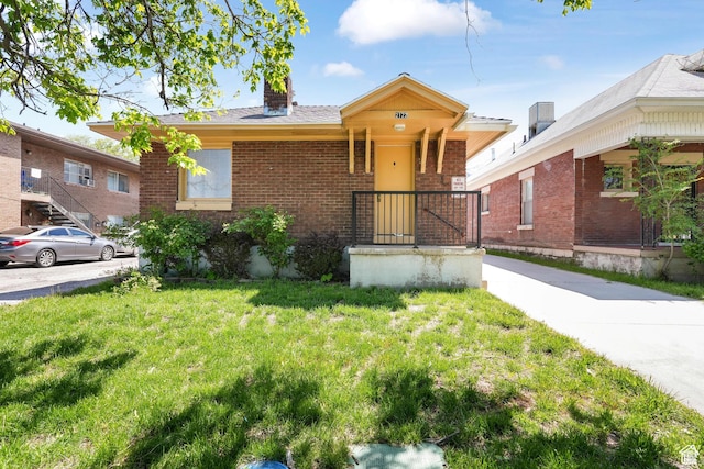 view of front of home featuring a front lawn, brick siding, and a chimney