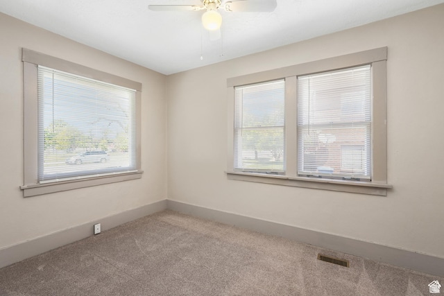carpeted spare room featuring healthy amount of natural light, a ceiling fan, and baseboards