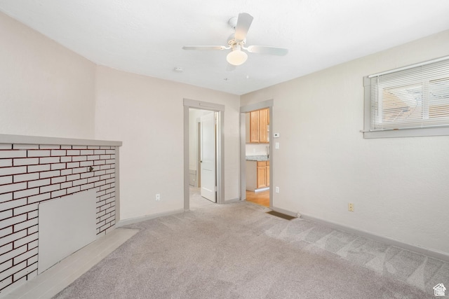 unfurnished living room featuring light carpet, a ceiling fan, and baseboards