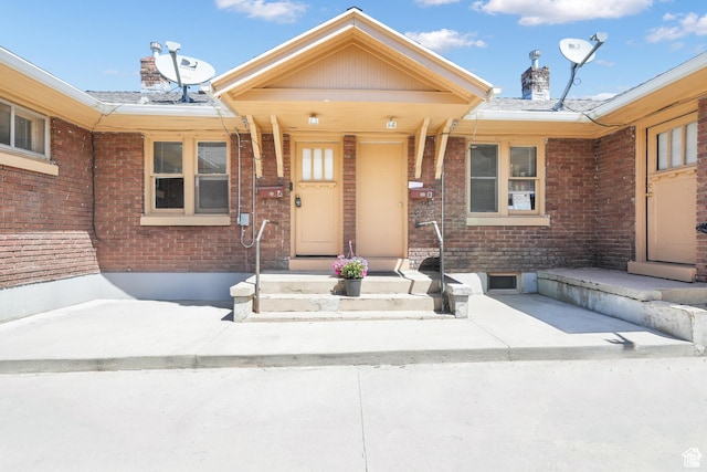 property entrance with a chimney and brick siding
