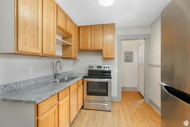 kitchen featuring stainless steel appliances, a sink, light wood finished floors, light stone counters, and open shelves