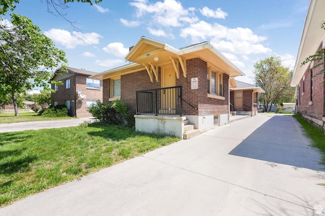 view of front of home with brick siding, a front yard, and concrete driveway