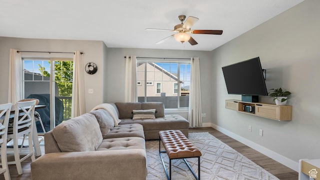 living room featuring healthy amount of natural light, ceiling fan, baseboards, and wood finished floors