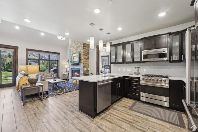 kitchen with stainless steel appliances, open floor plan, a sink, a peninsula, and light countertops