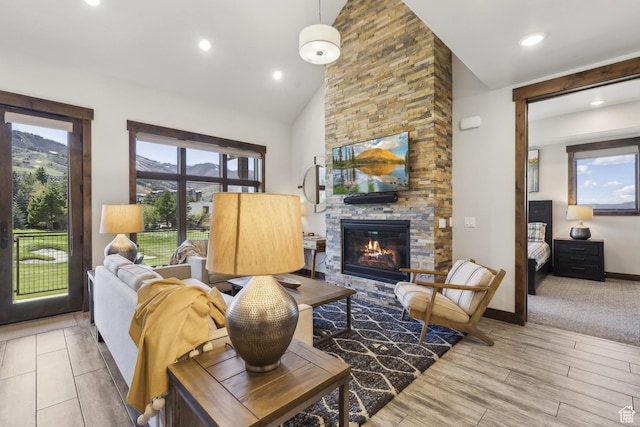 living area featuring a stone fireplace, recessed lighting, high vaulted ceiling, wood finished floors, and baseboards