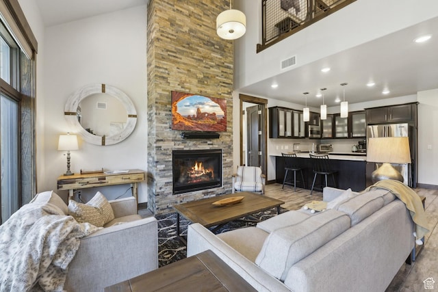 living room featuring a fireplace, a high ceiling, baseboards, and recessed lighting