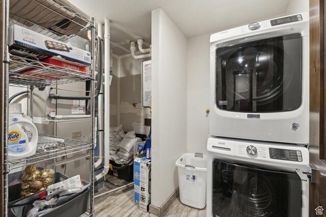 laundry room featuring stacked washer / drying machine, light wood-style flooring, and heating unit