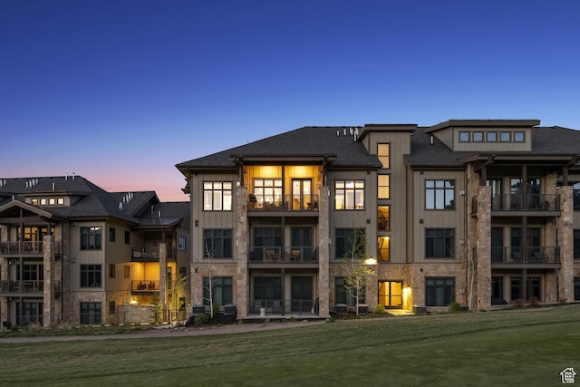 back of property at dusk with board and batten siding and a yard