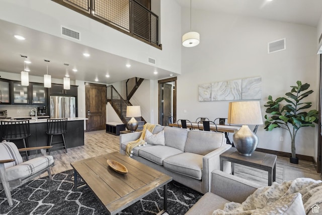 living room with light wood finished floors, stairs, high vaulted ceiling, and recessed lighting