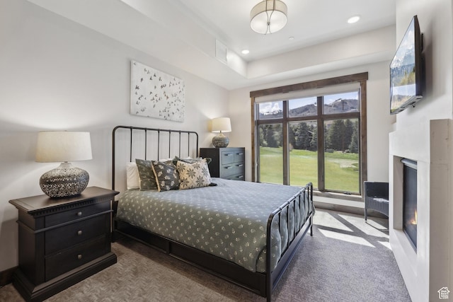 carpeted bedroom featuring a glass covered fireplace