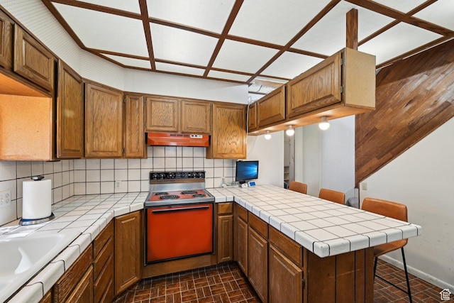 528 N Westcapitol St, Salt Lake City, UT 84103 - kitchen featuring range with electric stovetop, tile counters, under cabinet range hood, and a peninsula
