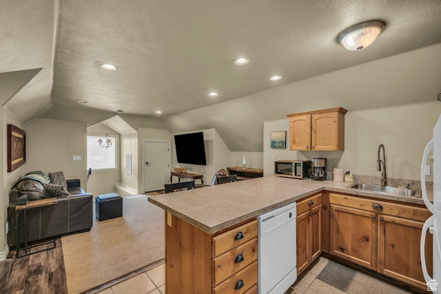 kitchen with dishwasher, open floor plan, a sink, vaulted ceiling, and a peninsula