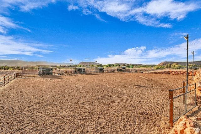 view of yard with an enclosed riding area, a mountain view, and a rural view