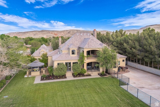 view of front of home with a gazebo, a chimney, a balcony, a patio area, and stucco siding