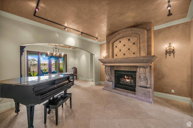 sitting room with rail lighting, arched walkways, a chandelier, a lit fireplace, and ornamental molding
