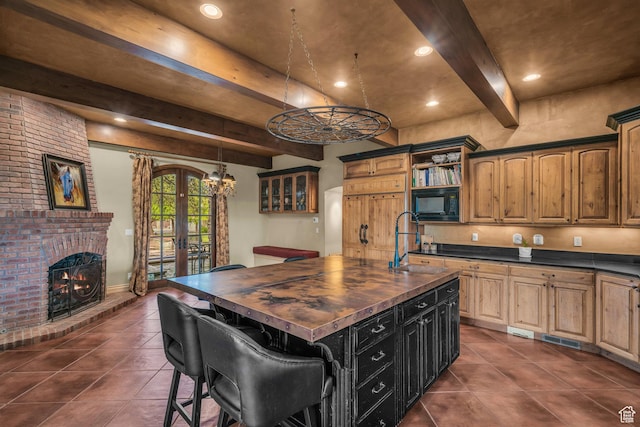 kitchen featuring a sink, wood counters, dark tile patterned floors, black microwave, and beam ceiling