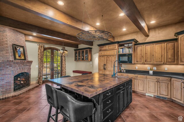 3770 Sugar Leo Rd, Bloomington, UT 84790 - kitchen featuring wooden counters, dark tile patterned flooring, black microwave, beamed ceiling, and a center island with sink