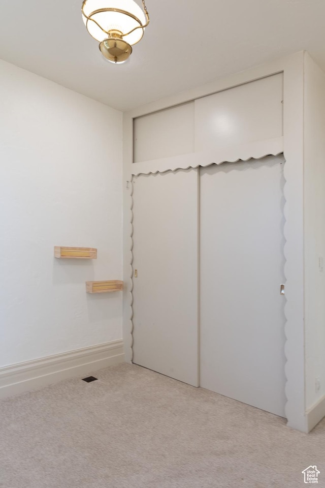 unfurnished bedroom featuring light colored carpet and a closet