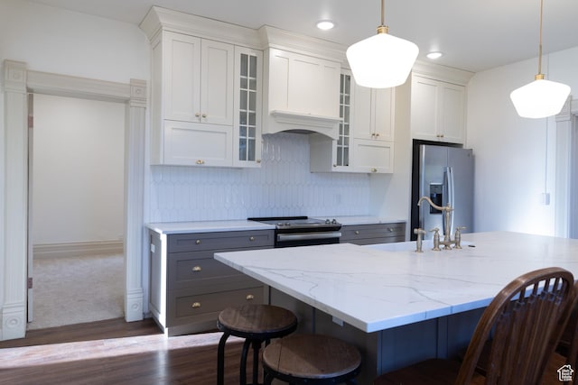 kitchen featuring appliances with stainless steel finishes, a kitchen bar, dark wood-type flooring, decorative light fixtures, and recessed lighting