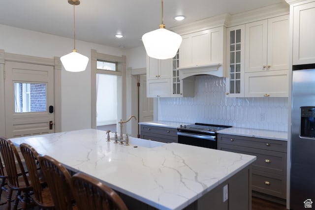kitchen featuring appliances with stainless steel finishes, gray cabinets, a sink, backsplash, and light stone counters
