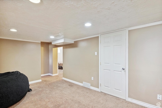 finished basement featuring recessed lighting, light colored carpet, baseboards, and a textured ceiling
