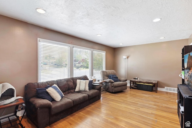 living area featuring a textured ceiling, light wood-type flooring, recessed lighting, and baseboards
