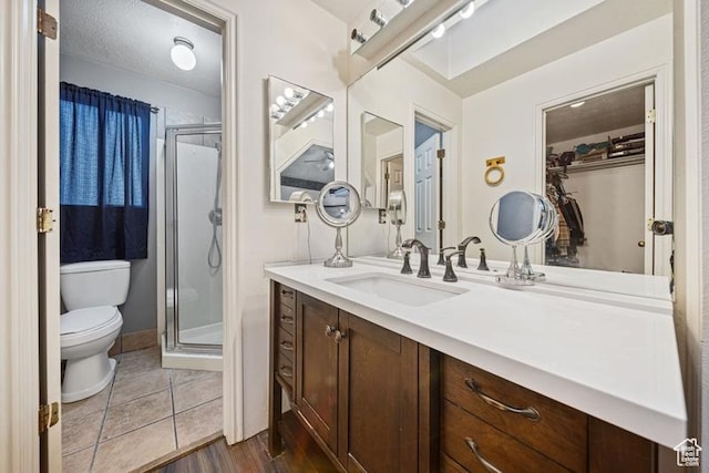 bathroom featuring toilet, a stall shower, vanity, and wood finished floors