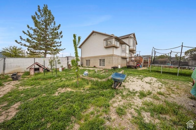 view of yard featuring a trampoline and a deck