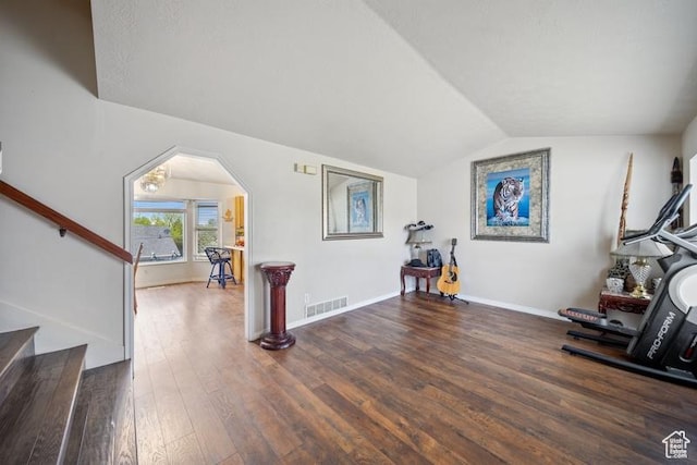workout room with wood finished floors, vaulted ceiling, baseboards, and arched walkways