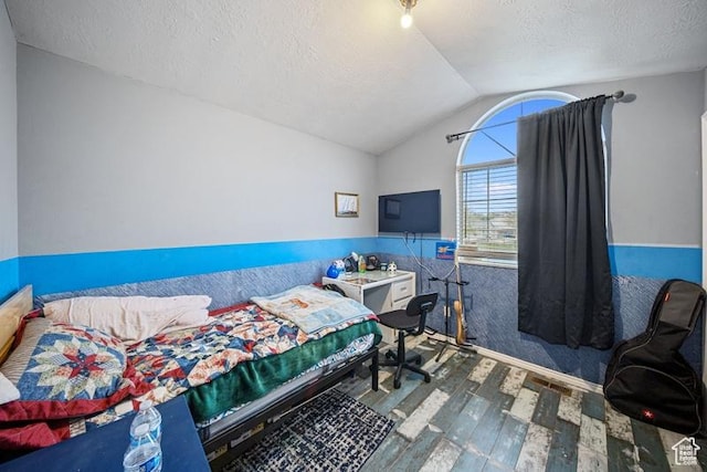 bedroom featuring wood finished floors, vaulted ceiling, and a textured ceiling