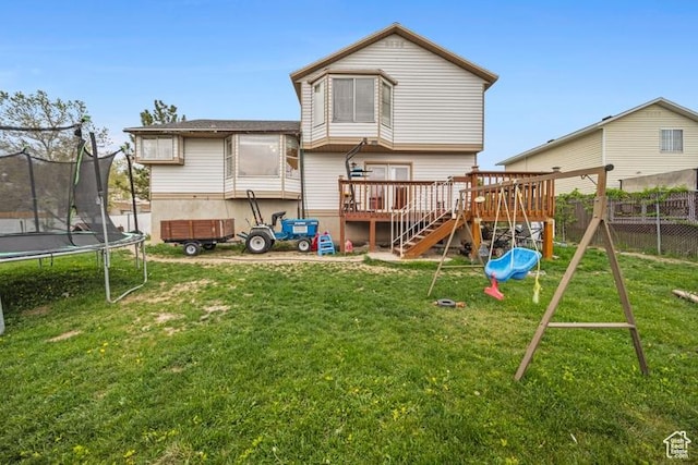 rear view of property featuring a trampoline, a playground, a deck, and stairs