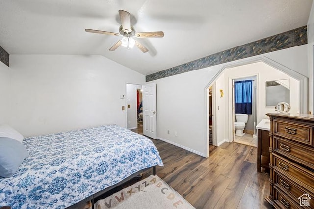 bedroom with dark wood-style floors, lofted ceiling, baseboards, ceiling fan, and ensuite bathroom