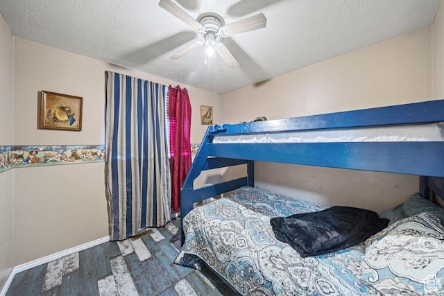 bedroom with wood finished floors, a textured ceiling, baseboards, and a ceiling fan