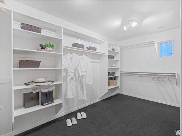 walk in closet featuring dark carpet