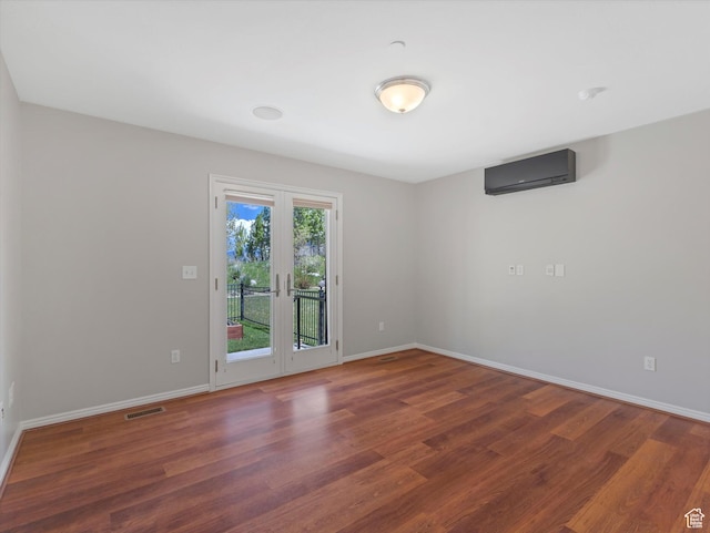 spare room with a wall mounted air conditioner, wood finished floors, and baseboards